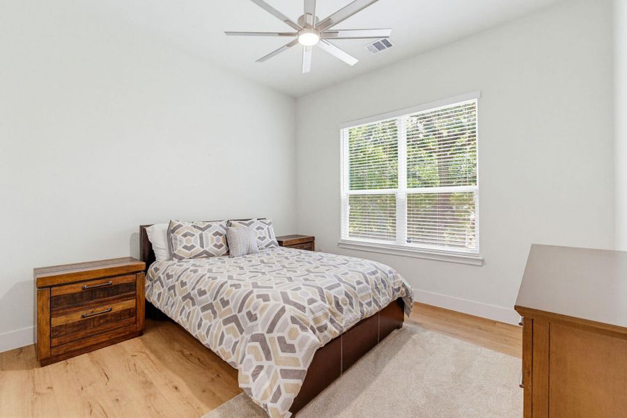 Hardwood floors and a bright window elevate this comfortable bedroom.