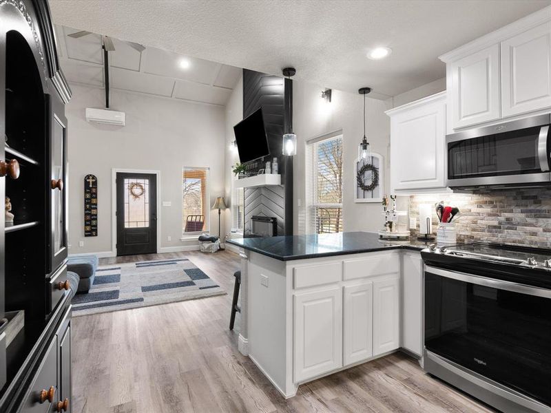 Kitchen featuring dark countertops, open floor plan, decorative backsplash, a peninsula, and stainless steel appliances