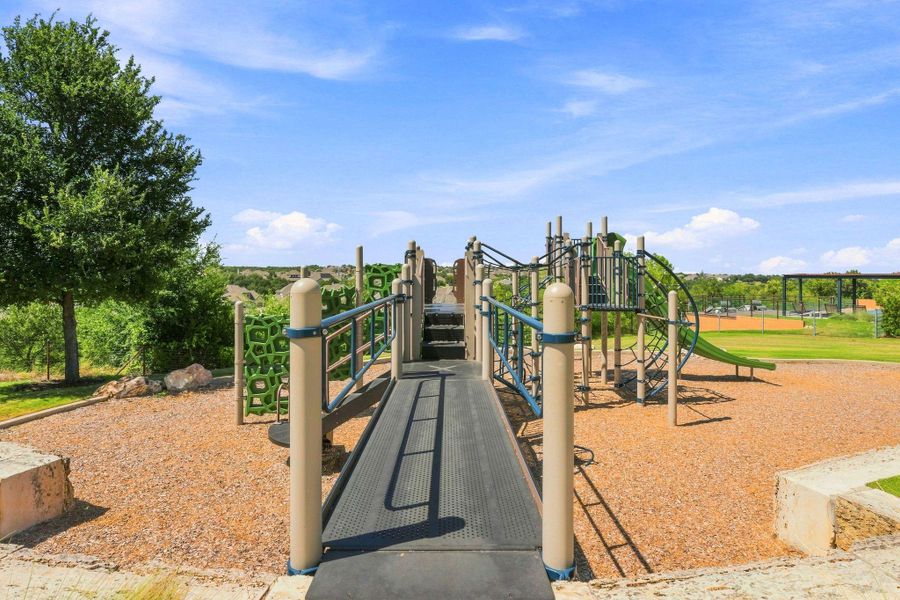 A well-maintained neighborhood playground sits under a clear blue sky.
