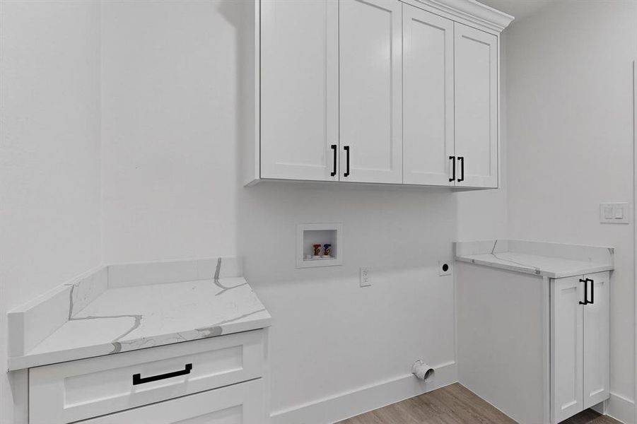 Washroom with light wood-style flooring, hookup for a washing machine, cabinet space, and hookup for an electric dryer