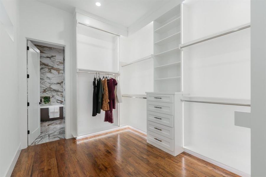 Spacious closet featuring hardwood floors, under mounted lighting, and organization. Spacious closet featuring hardwood floors, under mounted lighting, and organization.