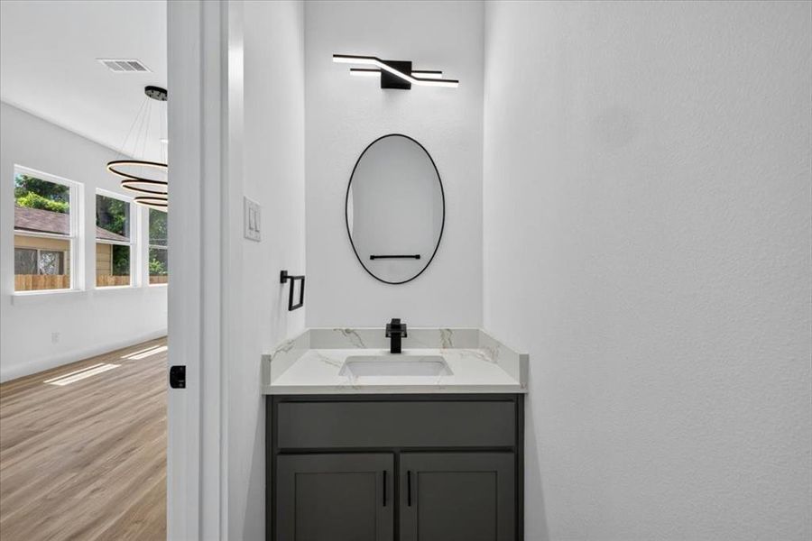 Vanity area with a gray shaker-style cabinet, white countertop, and integrated sink Vanity area with a gray shaker-style cabinet, white countertop, and integrated sink