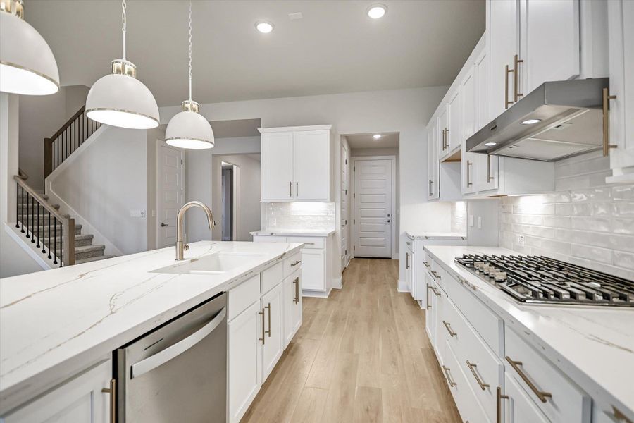 Polished stone counters and clean white cabinetry frame this modern culinary workspace with wood flooring. Polished stone counters and clean white cabinetry frame this modern culinary workspace with wood flooring.