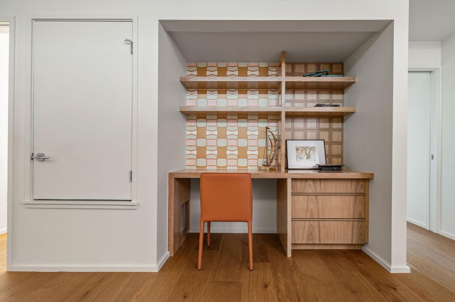 Bar area with built in desk, light wood-style flooring, and open shelves