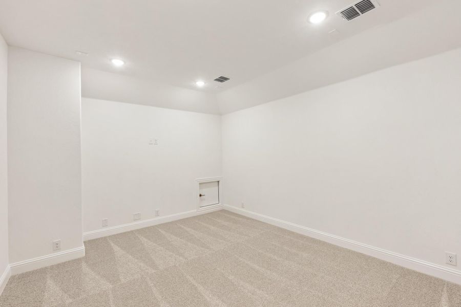 Empty room with white walls, beige carpet, recessed lighting, and a small access panel on the wall