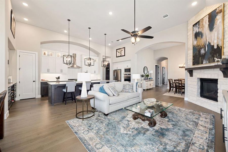 Living room featuring dark wood-type flooring, ceiling fan, and a brick fireplace