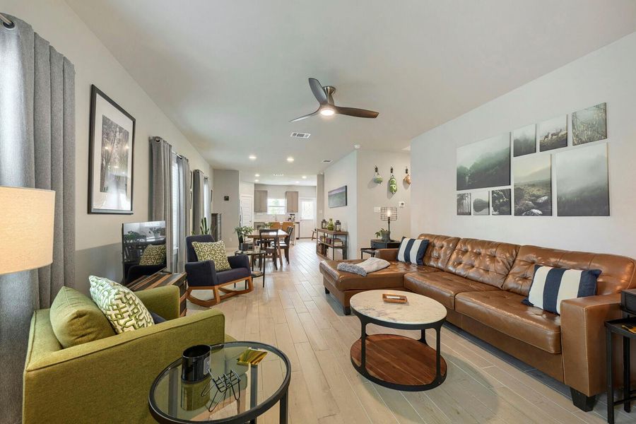 An inviting open-concept living area with light-toned hardwood flooring flows seamlessly into the dining and kitchen spaces. An inviting open-concept living area with light-toned hardwood flooring flows seamlessly into the dining and kitchen spaces.