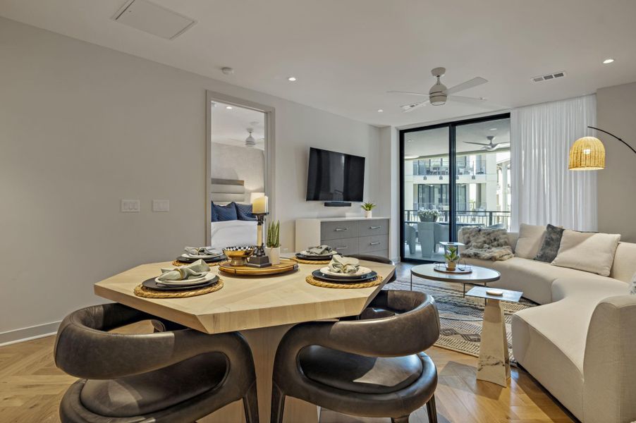 Herringbone hardwood floors extend through this open-concept living space with a dining area and balcony access.