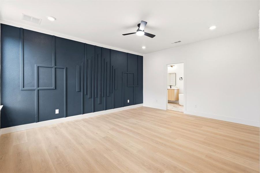 This spacious room features light-toned flooring and a striking accent wall with a geometric design
