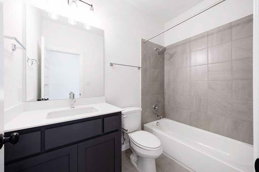 Bathroom featuring toilet, vanity, shower / tub combination, and tile patterned flooring Bathroom featuring toilet, vanity, shower / tub combination, and tile patterned flooring