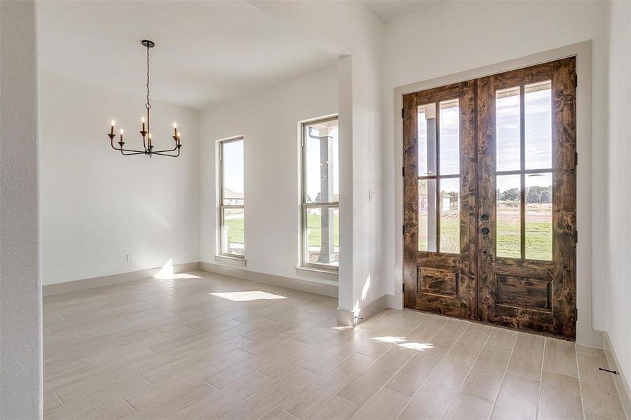 Foyer featuring french doors, light hardwood / wood-style floors, and a notable chandelier