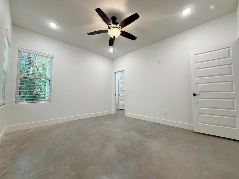 Unfurnished room featuring finished concrete flooring, ceiling fan, and recessed lighting