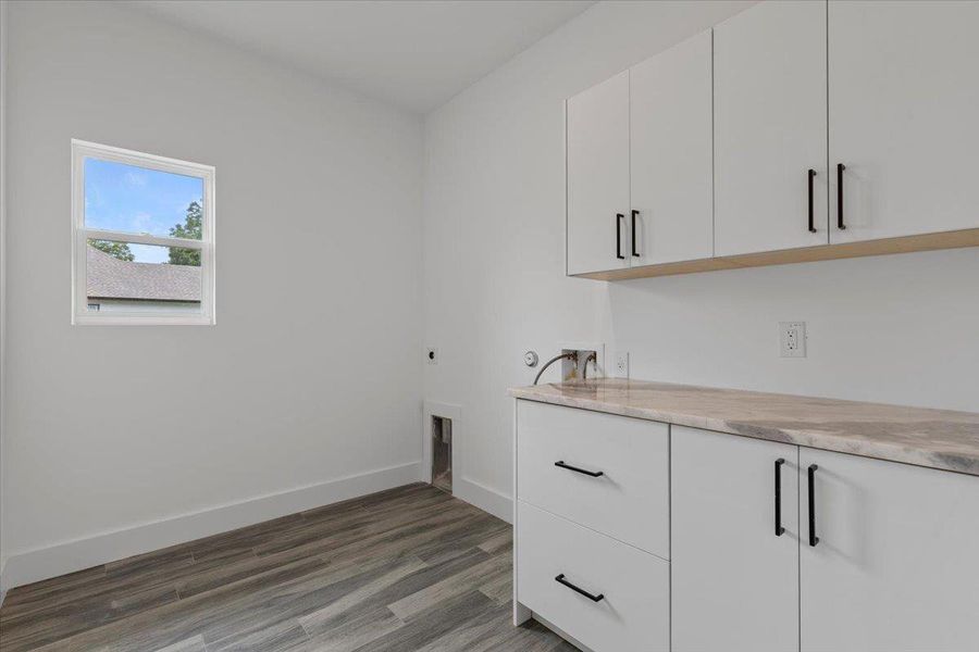 Laundry room featuring cabinet space, hookup for a washing machine, wood finished floors, and electric dryer hookup Laundry room featuring cabinet space, hookup for a washing machine, wood finished floors, and electric dryer hookup