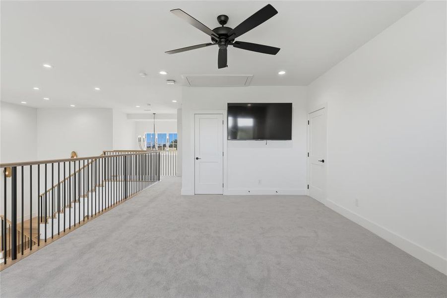 Carpeted loft area featuring a mounted television, a ceiling fan, and recessed lighting