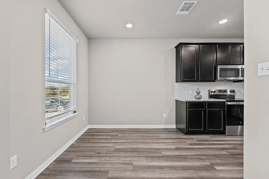 Bar featuring dark cabinets, appliances with stainless steel finishes, decorative backsplash, light wood finished floors, and recessed lighting Bar featuring dark cabinets, appliances with stainless steel finishes, decorative backsplash, light wood finished floors, and recessed lighting