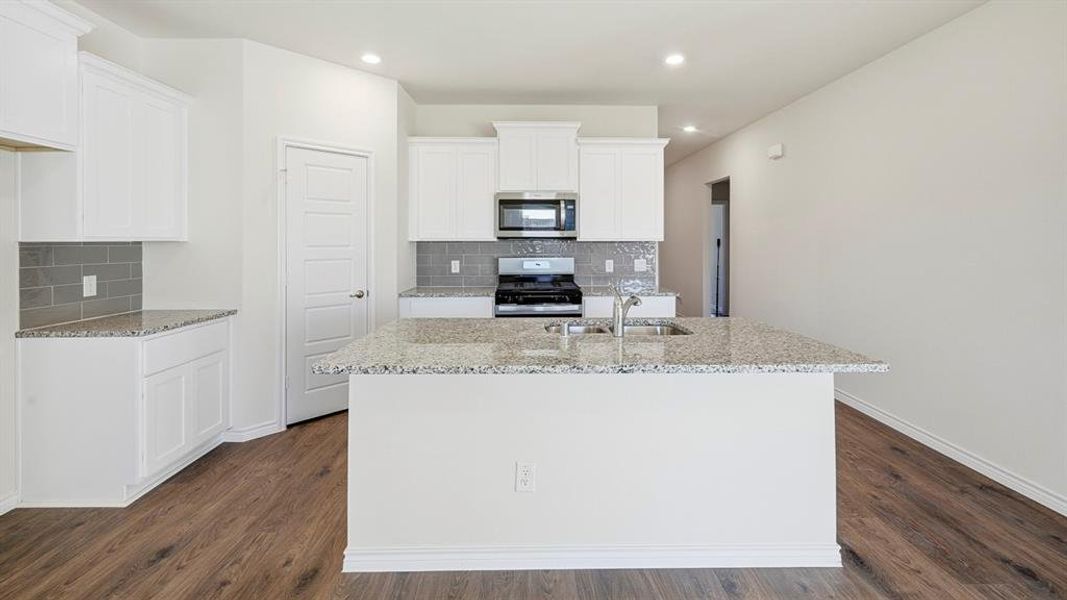 Kitchen featuring light stone counters, stainless steel appliances, backsplash, a center island with sink, and recessed lighting Kitchen featuring light stone counters, stainless steel appliances, backsplash, a center island with sink, and recessed lighting