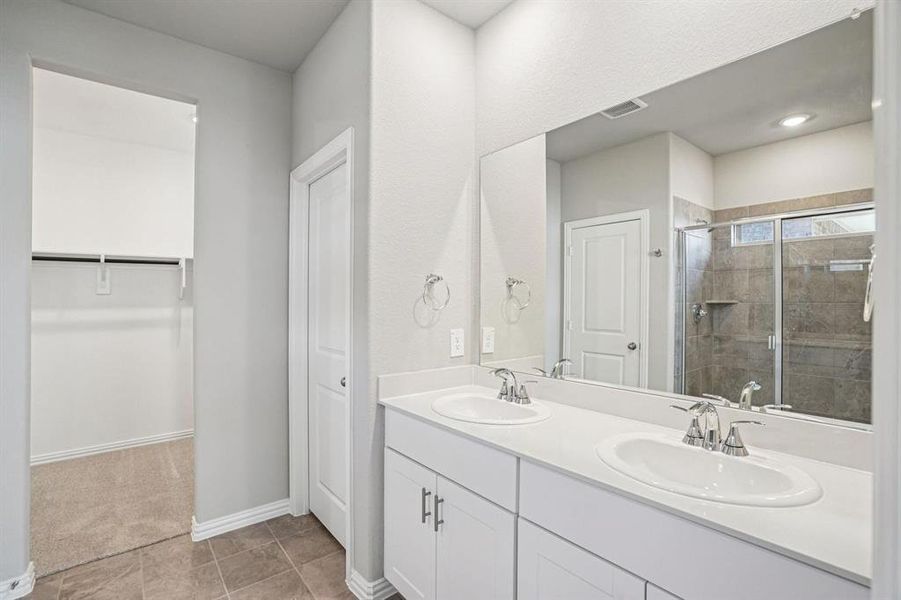 Bathroom with double vanity, a stall shower, and a walk in closet
