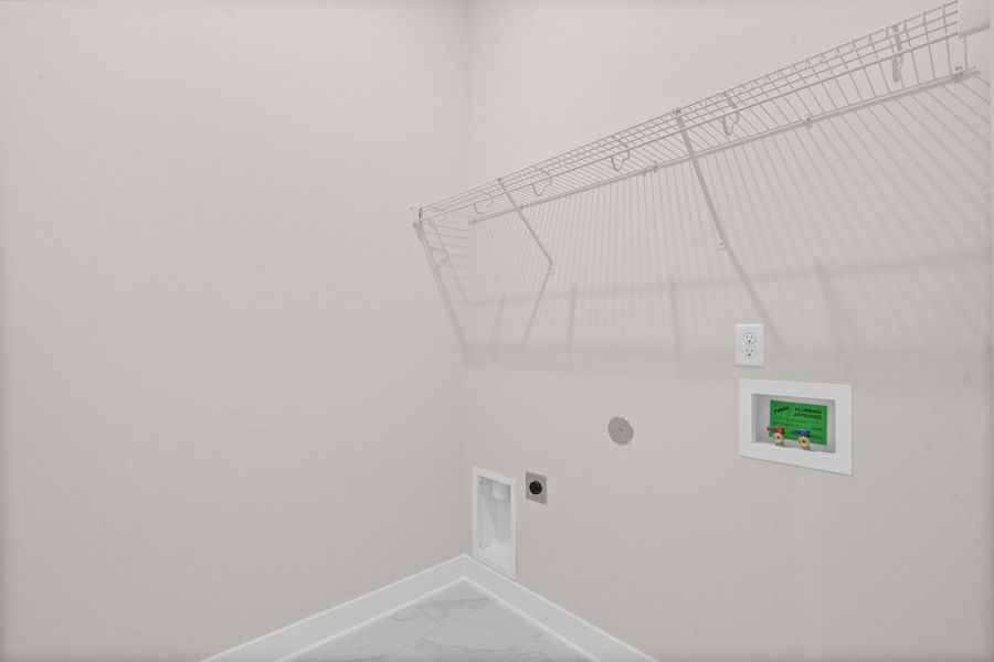 White wire shelving, wall-mounted electrical outlet, and plumbing hookups
