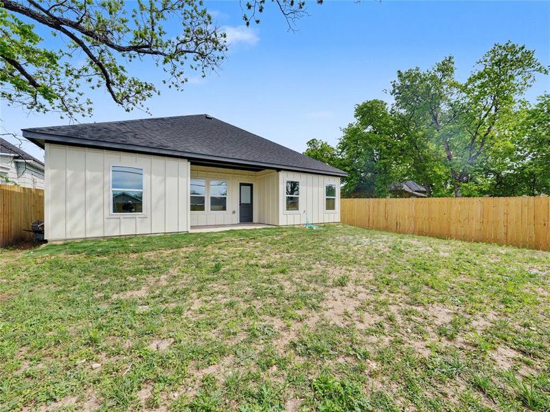 Rear view of property with a patio area, a fenced backyard, board and batten siding, and roof with shingles
