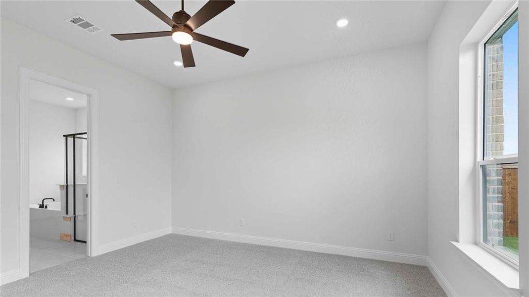 Spacious room with plush gray carpeting and a ceiling fan with integrated lighting