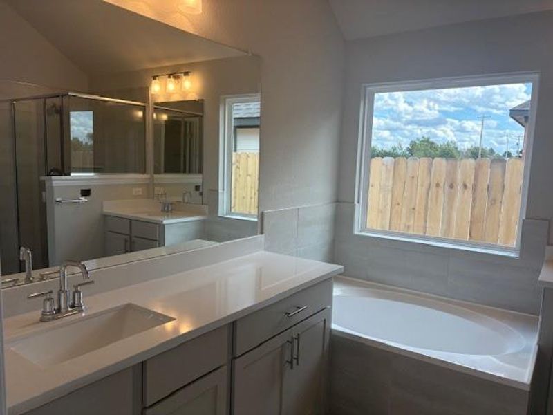 Full bath featuring a garden tub, vaulted ceiling, vanity, and a shower stall Full bath featuring a garden tub, vaulted ceiling, vanity, and a shower stall