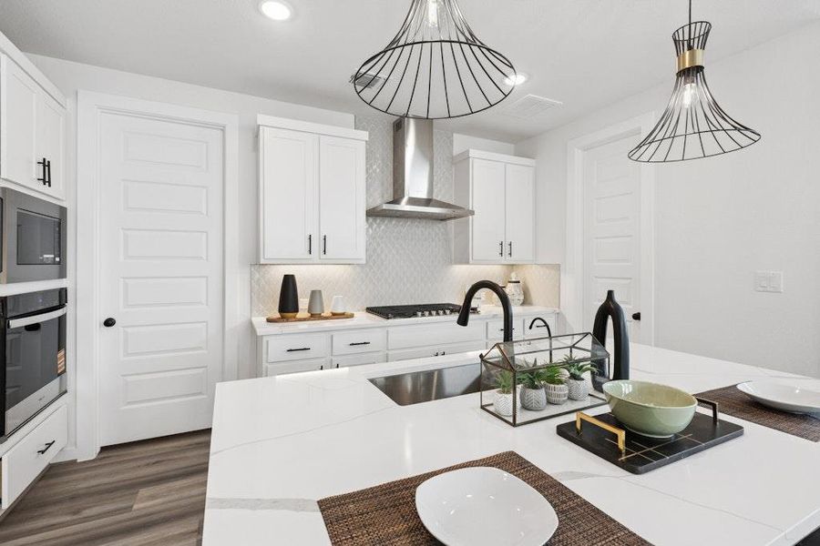 Kitchen featuring white cabinetry, stainless steel appliances, decorative backsplash, recessed lighting, and wall chimney exhaust hood Kitchen featuring white cabinetry, stainless steel appliances, decorative backsplash, recessed lighting, and wall chimney exhaust hood