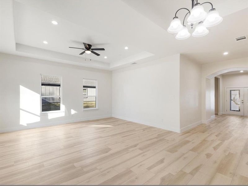 Unfurnished room featuring arched walkways, light wood-style floors, recessed lighting, a chandelier, and ceiling fan