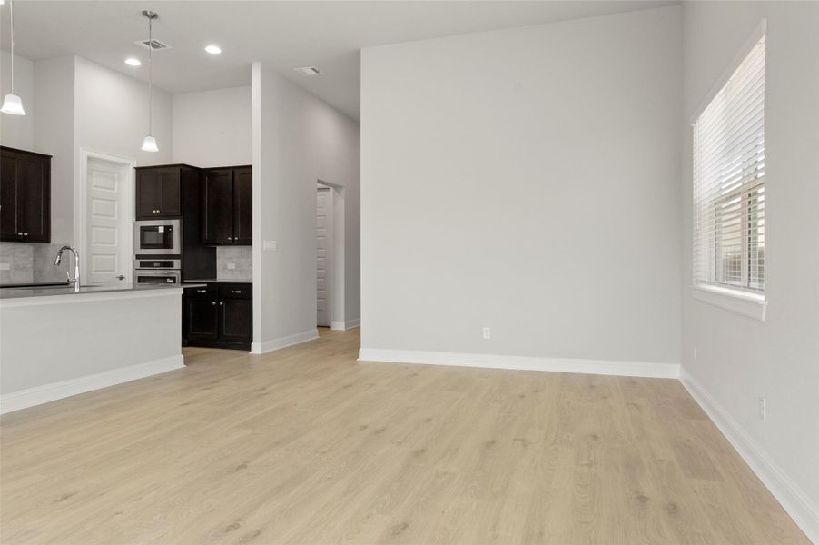 Kitchen featuring tasteful backsplash, light wood-type flooring, stainless steel oven, open floor plan, and built in microwave