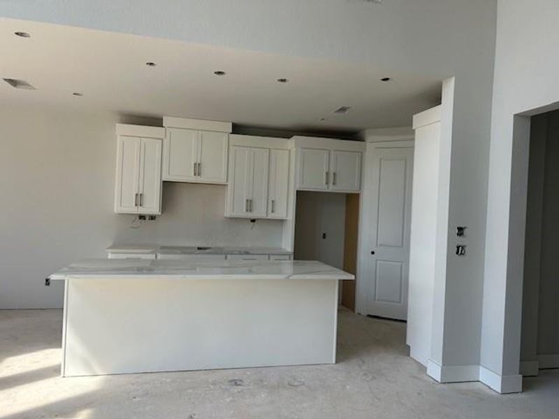 Kitchen featuring light cabinets with gold hardware.  Under cabinet lighting included.