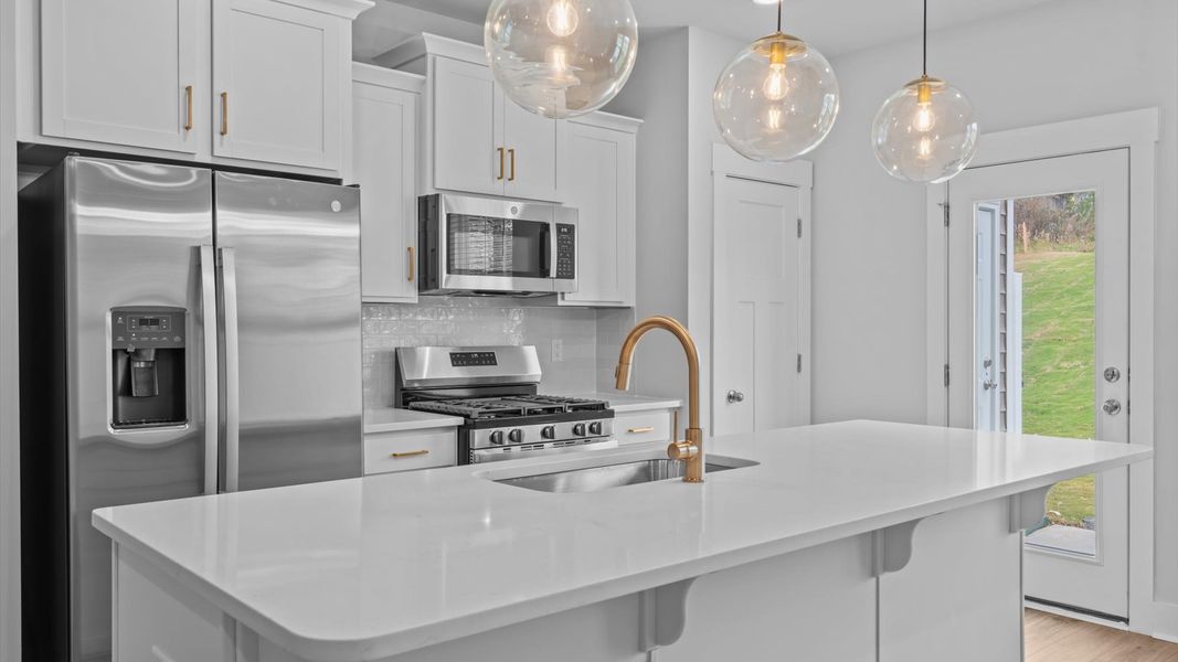 Highly skilled kitchen design includes a 9-foot island, quartz countertops, and stylish pendant fixtures Highly skilled kitchen design includes a 9-foot island, quartz countertops, and stylish pendant fixtures