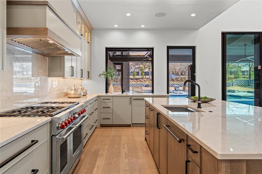 Quartzite countertops and backsplash. Wolf range, TWO Cove dishwashers, passthrough window to patio bar.