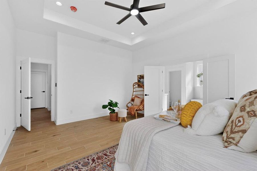Bedroom with a tray ceiling, wood tiled floors, ceiling fan, and recessed lighting