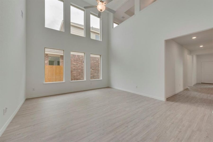 Unfurnished room featuring light hardwood / wood-style flooring, ceiling fan, and a towering ceiling