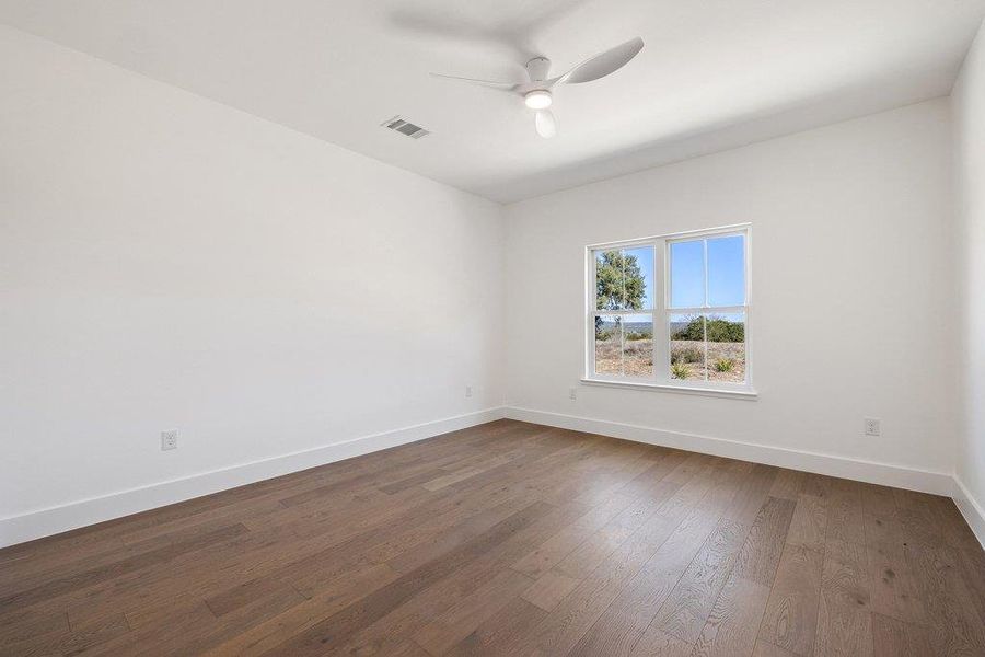 Unfurnished room featuring dark wood-style flooring and ceiling fan