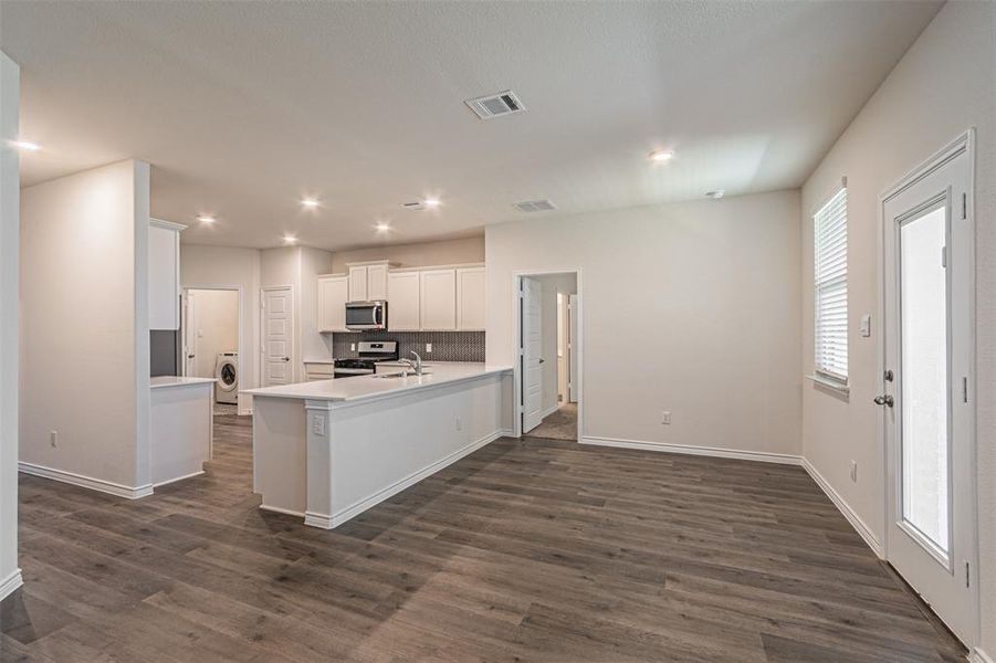 Kitchen with washer / clothes dryer, dark wood-type flooring, white cabinetry, and stainless steel appliances