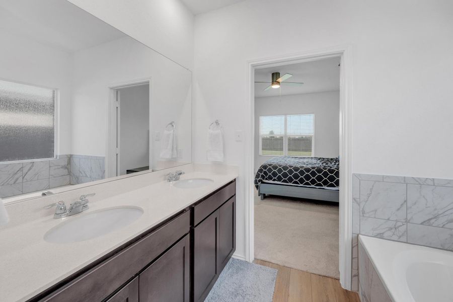 Bathroom featuring a bath, double vanity, a sink, and a ceiling fan
