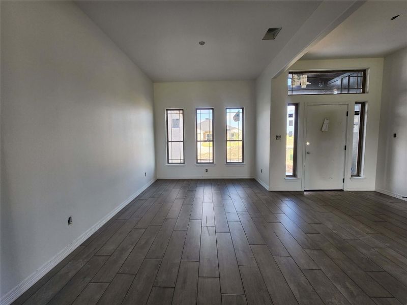 Spacious living area featuring wood-finish plank flooring, white baseboards, and high ceilings
