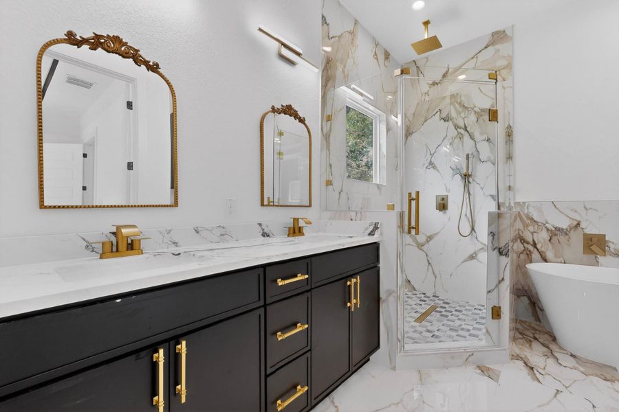 Marble finishes and golden accents create an elegant, contemporary bathing space.