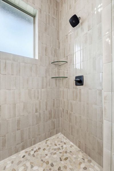 A refreshing shower enclosure with neutral-toned tiled walls and a natural stone pebble floor. A refreshing shower enclosure with neutral-toned tiled walls and a natural stone pebble floor.