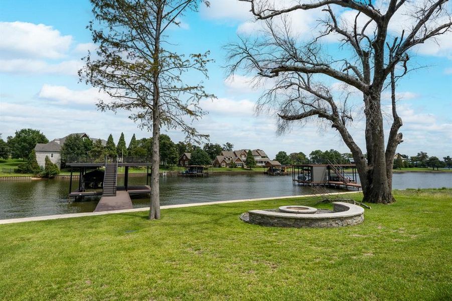 View of dock featuring a water view, a yard, and a fire pit