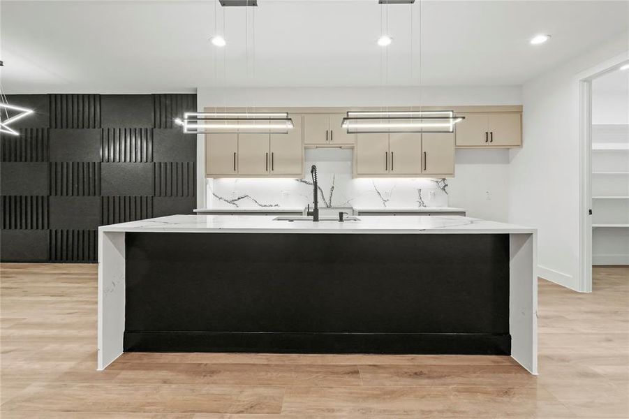 Kitchen featuring light stone countertops, an island with sink, light wood-type flooring, recessed lighting, and decorative light fixtures Kitchen featuring light stone countertops, an island with sink, light wood-type flooring, recessed lighting, and decorative light fixtures