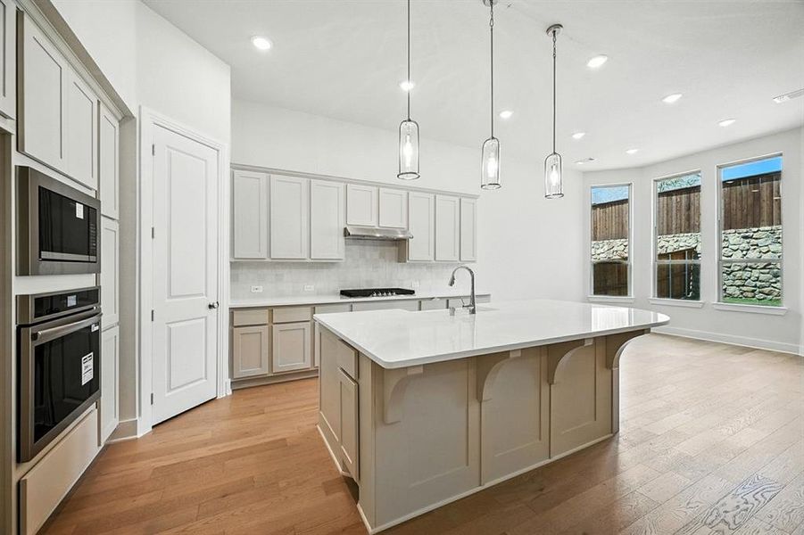 Kitchen featuring backsplash, light wood-style flooring, appliances with stainless steel finishes, recessed lighting, and a center island with sink Kitchen featuring backsplash, light wood-style flooring, appliances with stainless steel finishes, recessed lighting, and a center island with sink