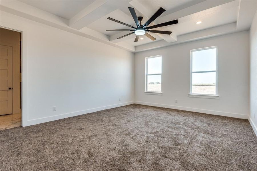 Carpeted spare room featuring ceiling fan and beamed ceiling