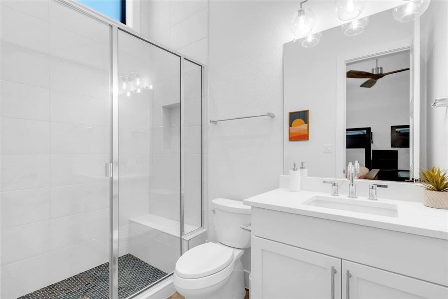 Bathroom two: High ceilings and a glass-enclosed walk-in shower elevate this pristine, modern bathroom.