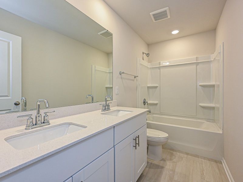 The secondary bathroom features dual-sinks and an oversized shower tub.