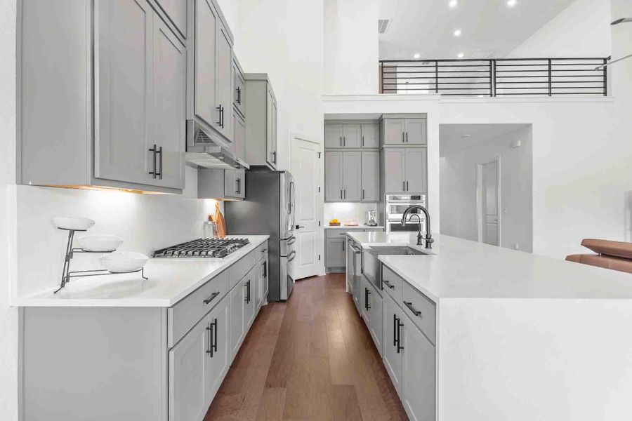 Modern kitchen featuring light gray cabinetry with black hardware, white countertops, and wood-finish flooring