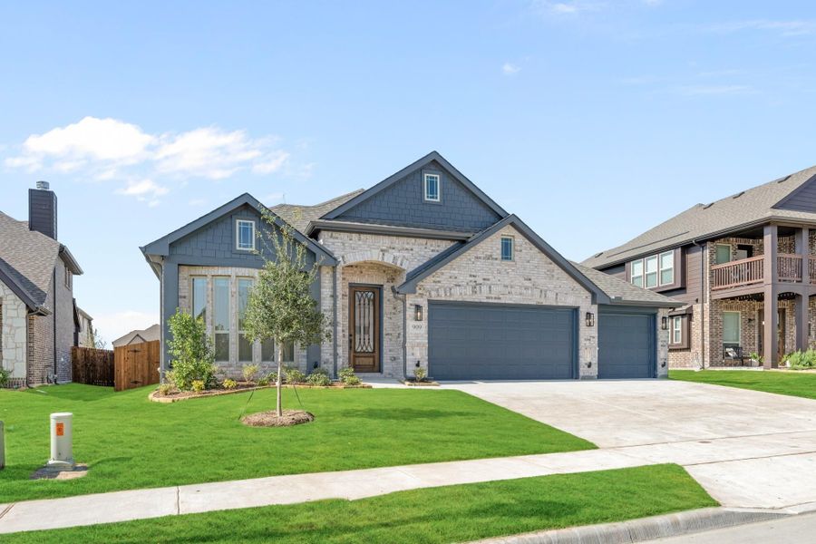 Single-story home with stone and gray siding exterior, two-car garage, arched entry, and manicured front lawn