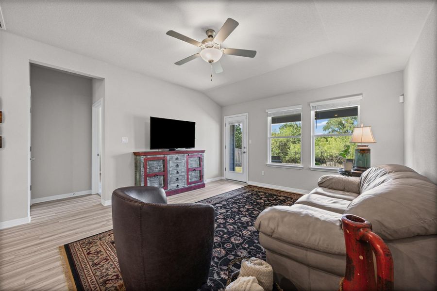 Natural light streams through large windows, showcasing the vaulted ceilings and wood-style flooring.