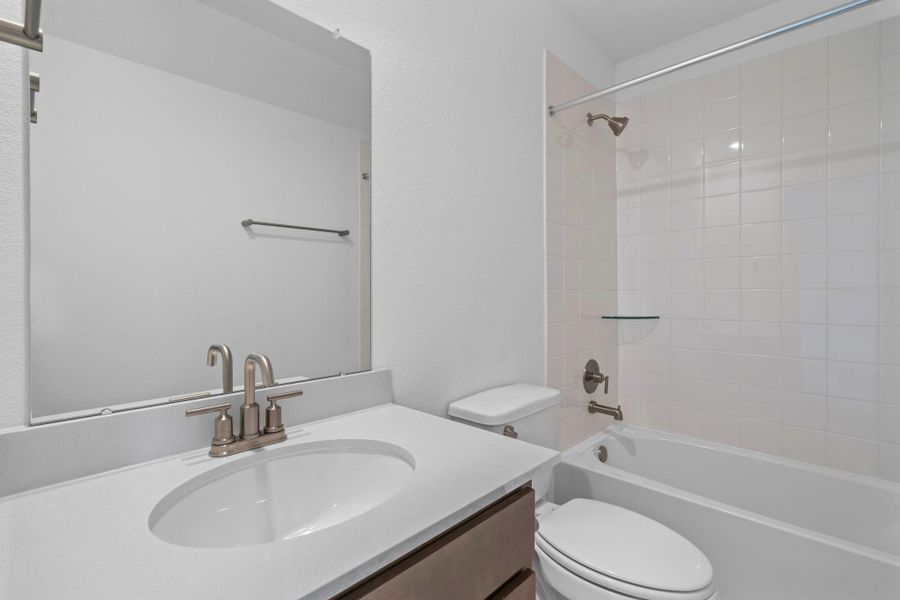 The secondary bath features tile flooring, white cabinetry and light countertops and a shower/tub combo. Perfect for accommodating any visiting family and friends.