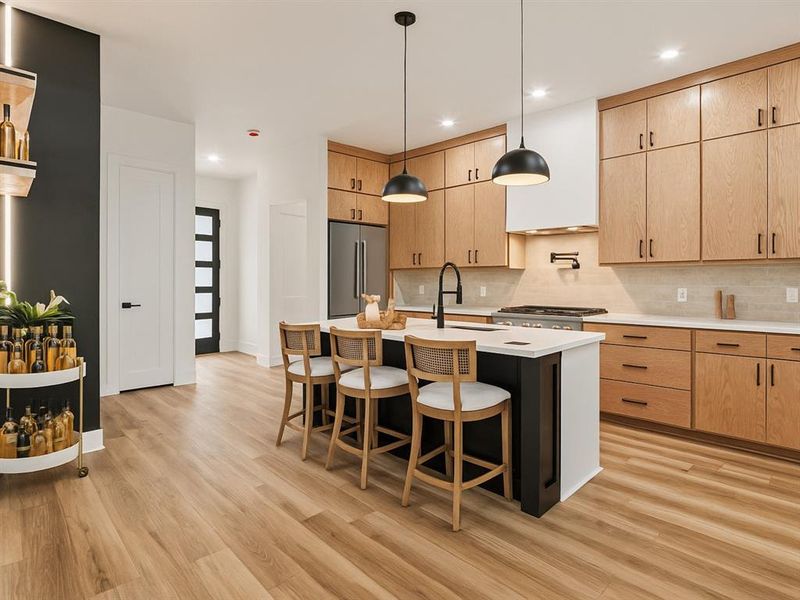 Kitchen with light brown cabinetry, pendant lighting, light stone counters, a breakfast bar area, and backsplash